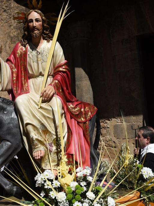 Ein Bildnis einer christlichen Ikone namens "La borriquilla", das den triumphalen Einzug Jesu in Jerusalem darstellt, wird von Büßern während der Prozession des Palmsonntags in Almazán, Nordspanien, getragen.
