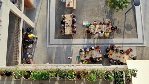 Draufsicht auf viele Menschen, die in einem offenen Innenhof in der Heizenholz Siedlung in Zürich gemeinsam an mehreren Tischen essen. Bild: Katrin Simonett