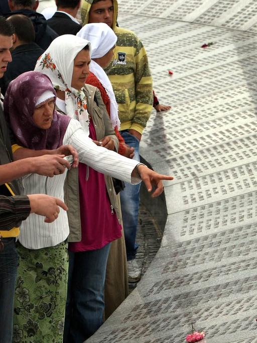 Besucher lesen die Namen von bosnischen Muslimen, die beim Massaker vom Srebrenica umgebracht worden.