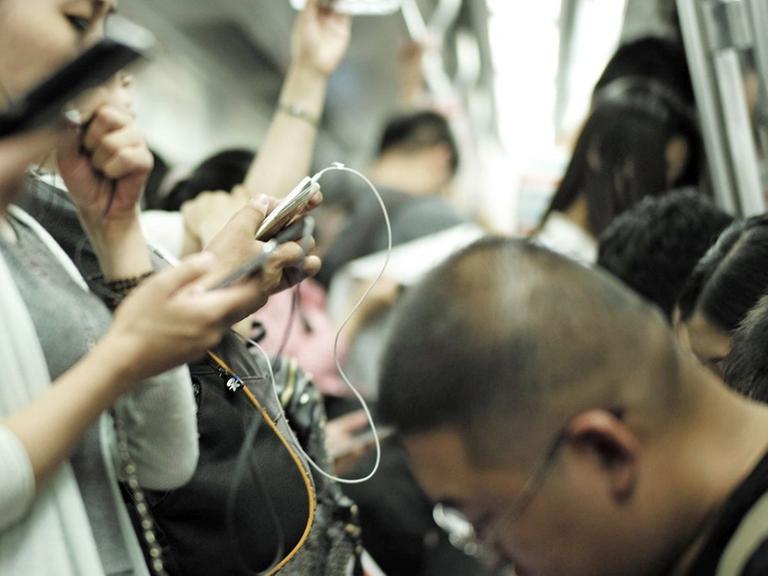 Fahrgäste in einer U-Bahn benutzen ihre Smartphones.