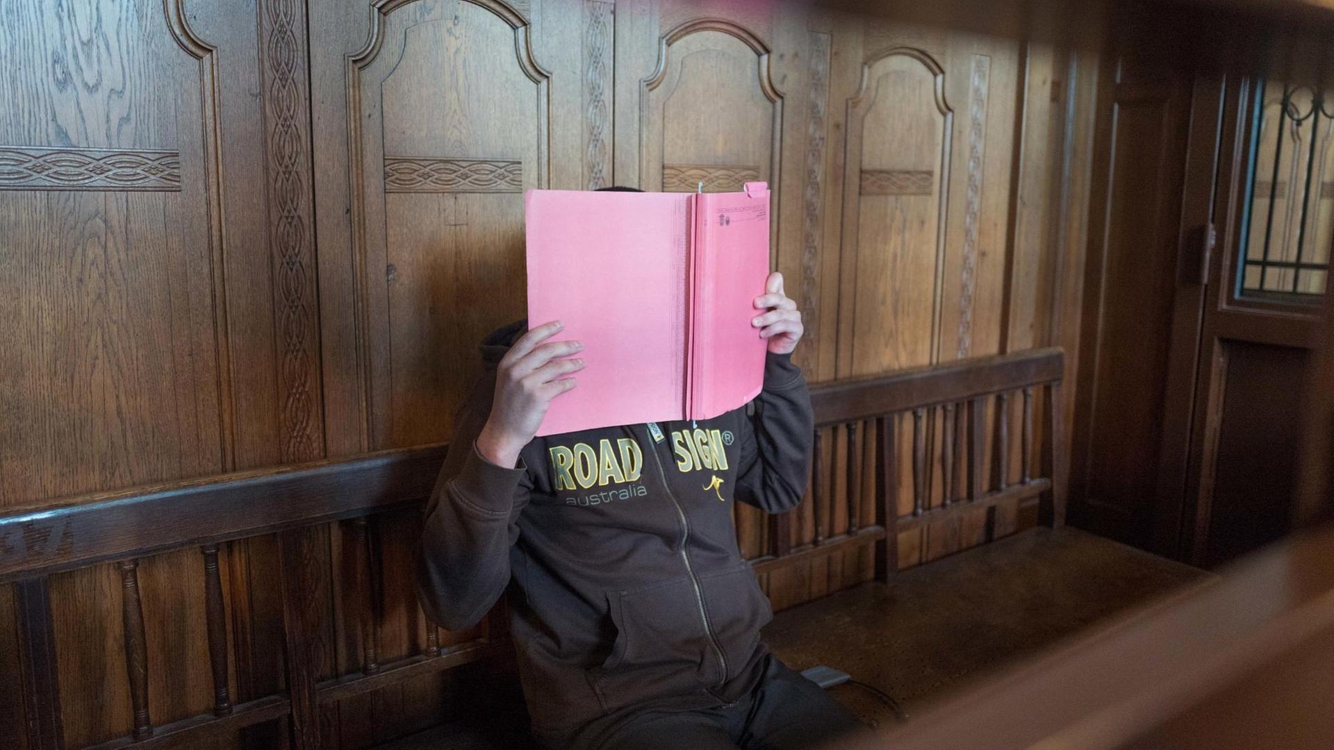 Der Angeklagte Wajid S. sitzt auf einer Bank im Kammergericht in Berlin und hält sich eine Akte vor das Gesicht. Gegen den 26-Jährigen hat ein Prozess wegen Mitgliedschaft in der terroristischen Vereinigung Taliban begonnen.