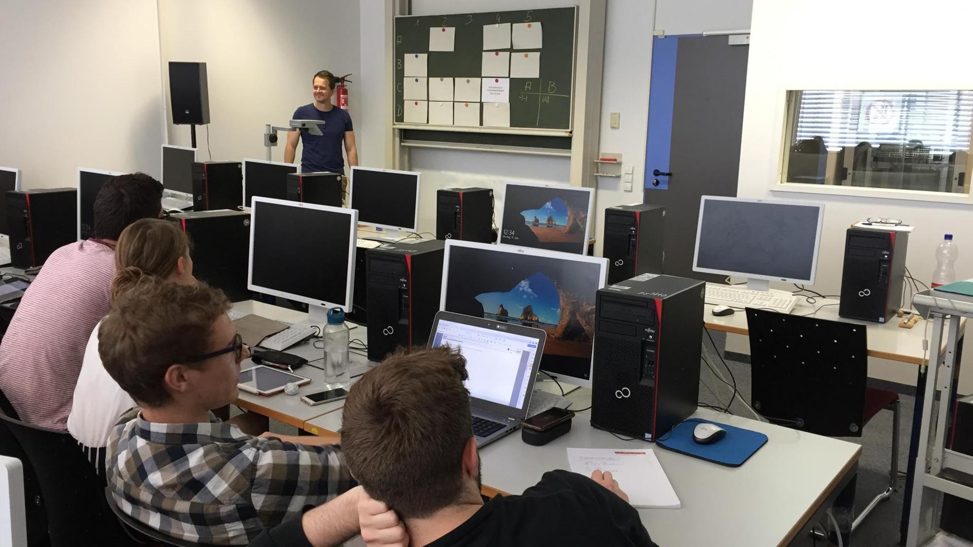 Der Dozent Dr. Stefan Fedtke steht im Computerraum und bespricht mit Studierenden ein Simulationsprojekt