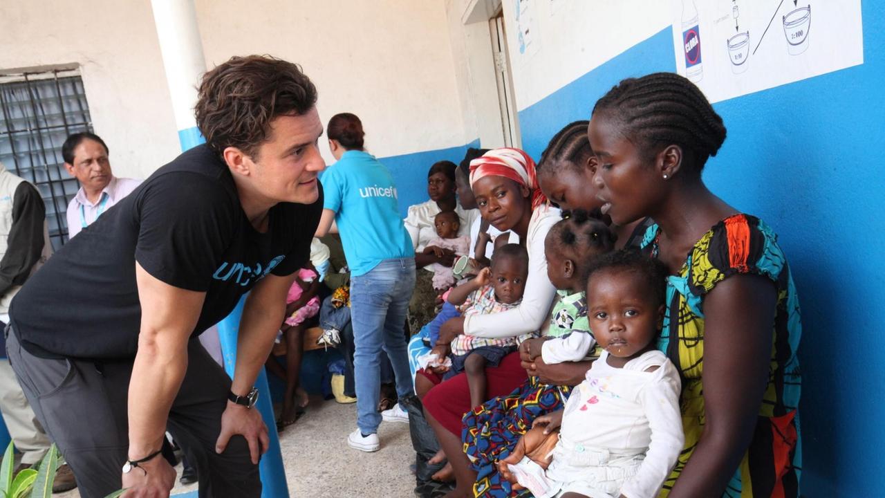 Liberia, 23 März 2015: Der britische Schauspieler und Unicef-Botschafter Orlando Bloom spricht mit einer Mutter und ihrem Kind vor einer Klinik.