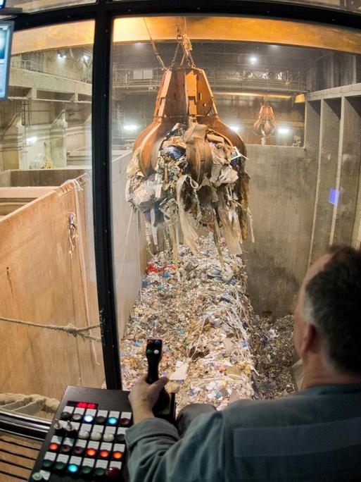 Ein Kraftwerker transportiert Müll mit einem Kran zum Verbrennen in einer Müllverbrennungsanlage der EEW Energy from Waste in Hannover.