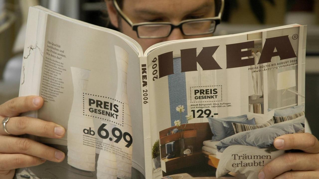 Ein Mann liest einen Katalog des Einrichtungshauses IKEA.