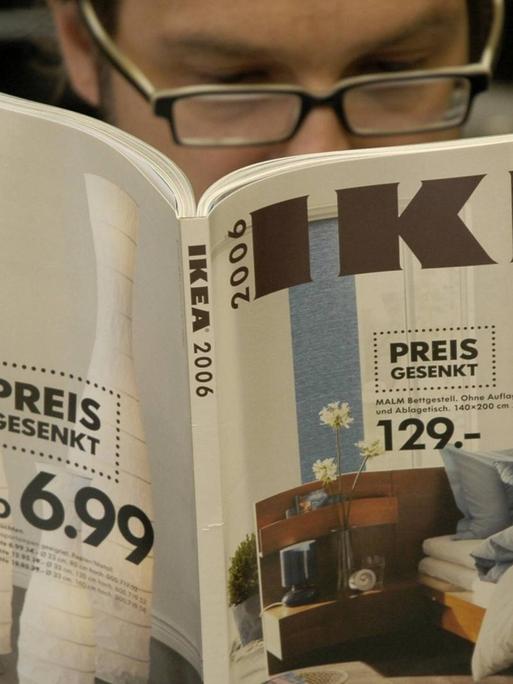 Ein Mann liest einen Katalog des Einrichtungshauses IKEA.