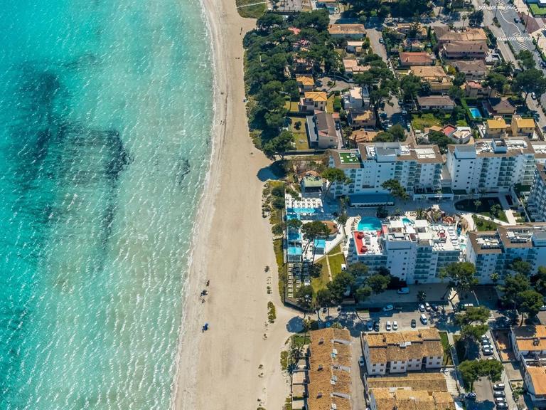 Luftaufnahme vom Strand von Alcúdia mit angrenzenden Hotelanlagen.