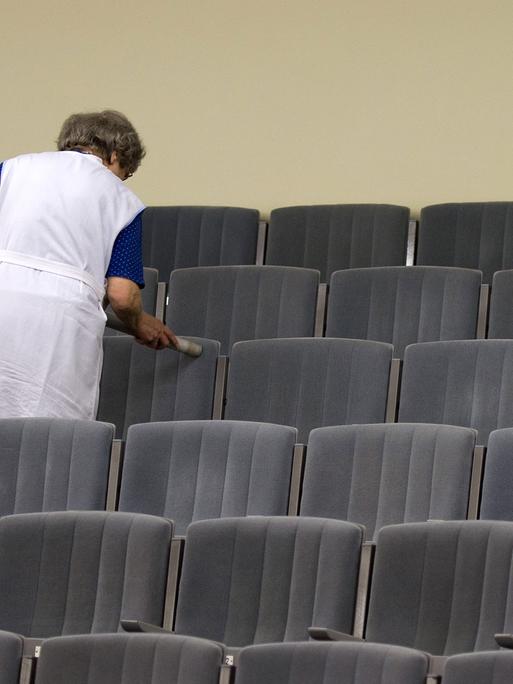 Eine Mitarbeiterin des Theaters in Meißen (Sachsen) reinigt mit einem Staubsauger die Sitze im Zuschauersaal des Theaters.
