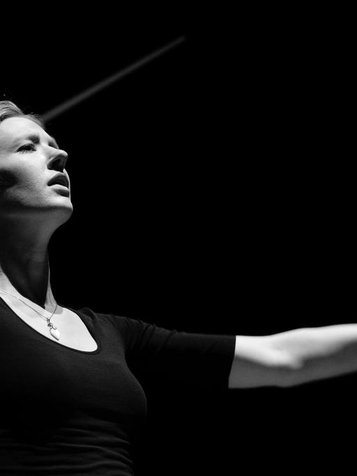 Eine kontrastreiche schwarz-weiß Aufnahme zeigt die Dirigentin Joana Mallwitz in Aktion.