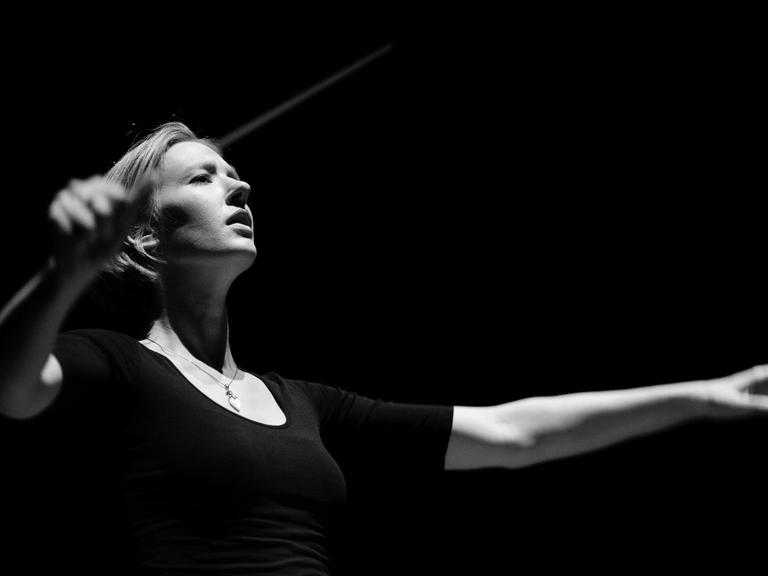 Eine kontrastreiche schwarz-weiß Aufnahme zeigt die Dirigentin Joana Mallwitz in Aktion.