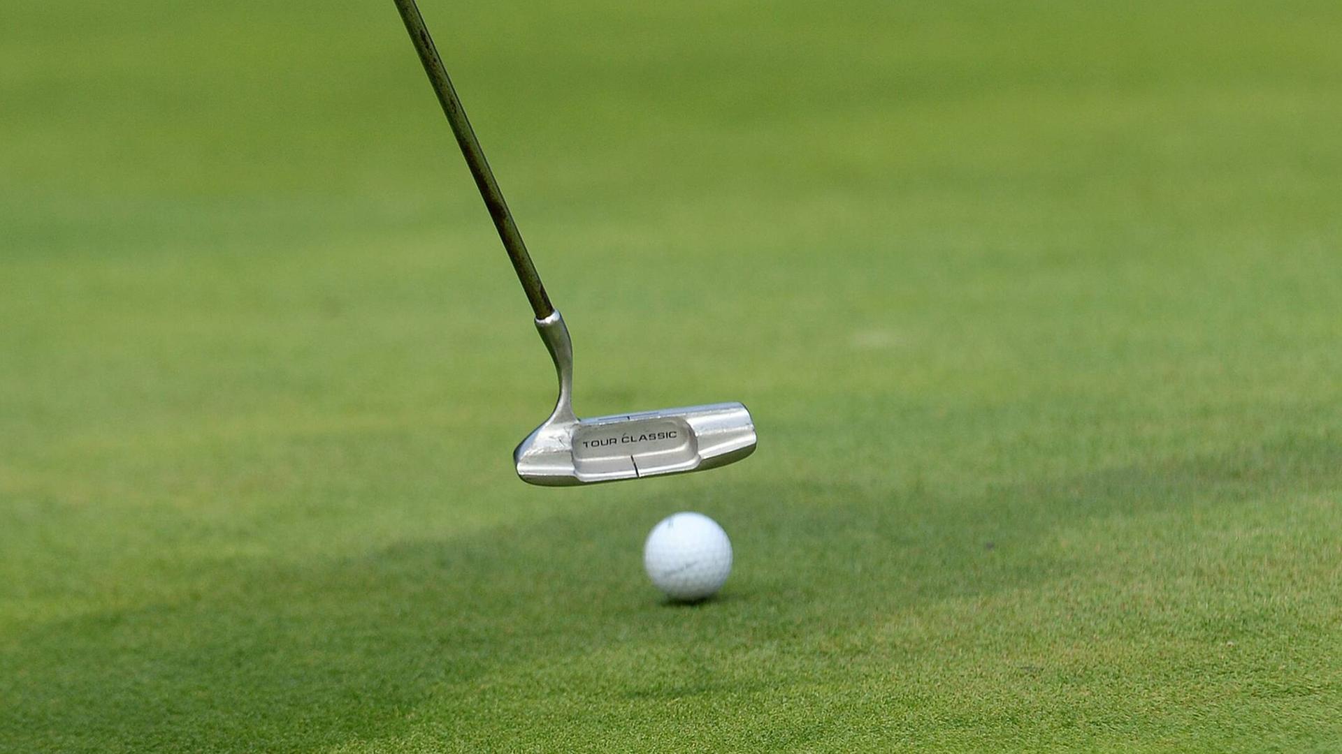 Golfschläger und Ball auf grünem Rasen