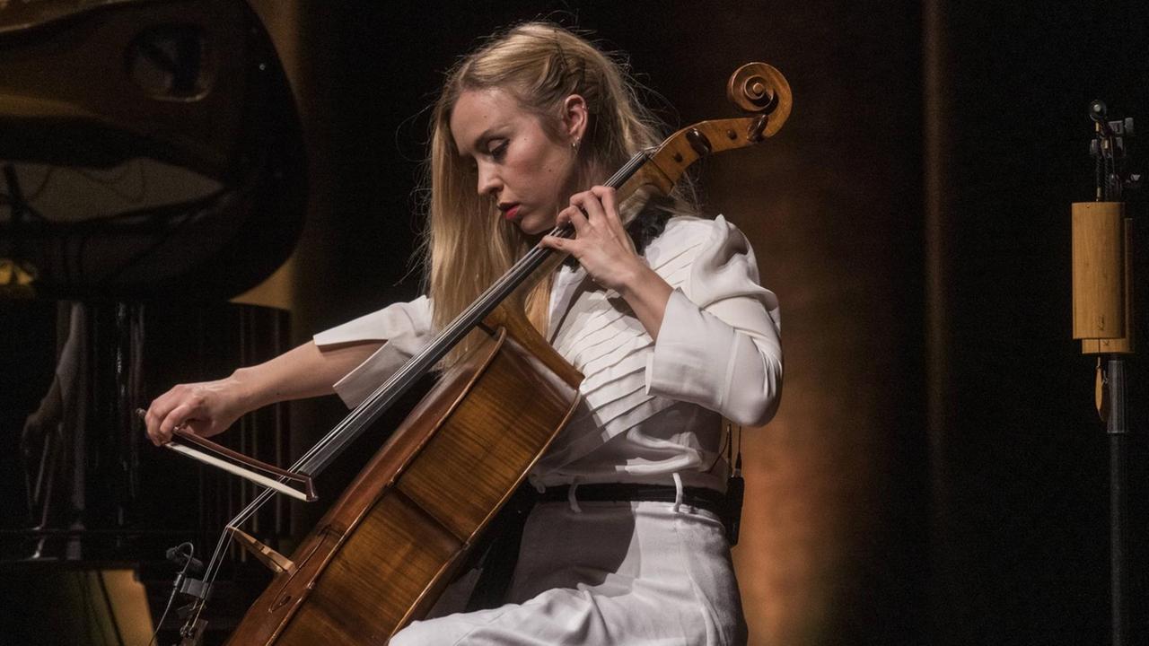 Eine Frau sitz auf einer Bühne und spielt Cello