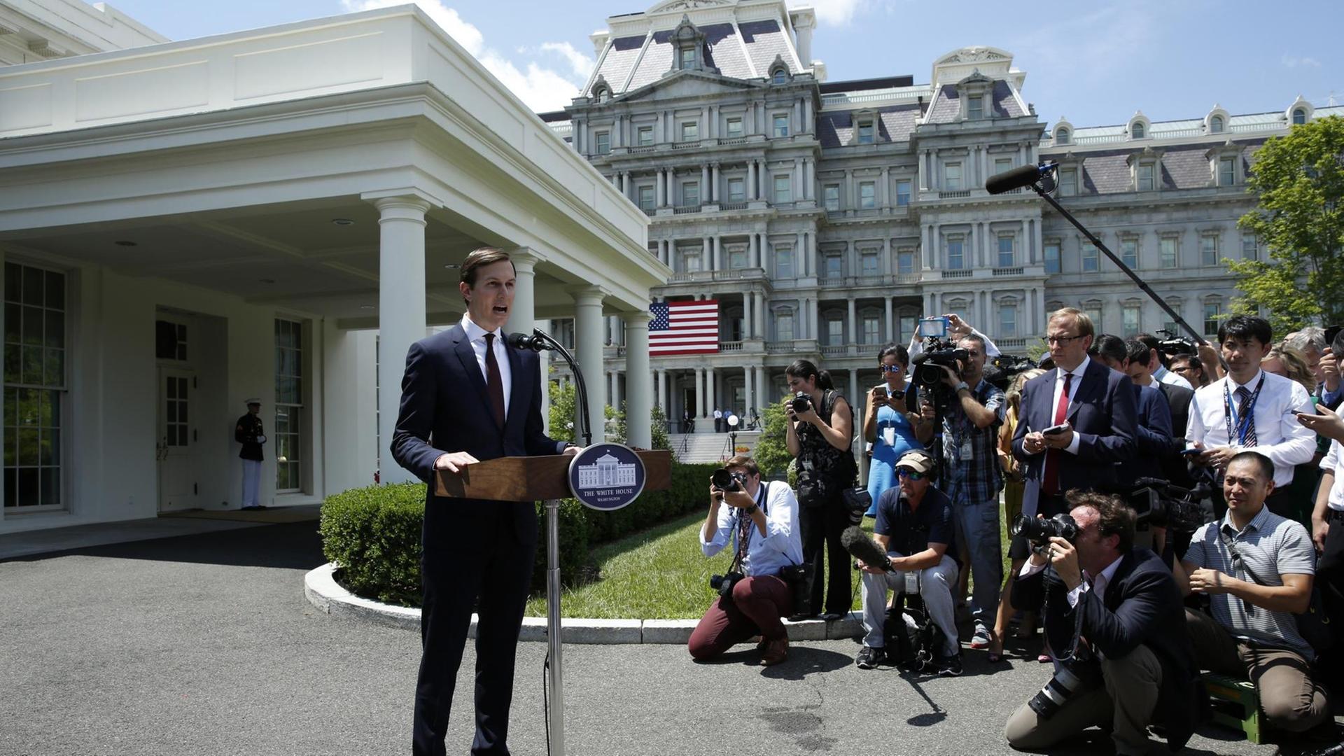 Der Schwiegersohn und Berater von US-Präsident Trump, Jared Kushner, gibt vor dem Weißen Haus in Washington ein Statement ab. Er steht hinter einem Podest mit einem Mikrofon, vor ihm stehen und sitzen Reporter und Fotografen.