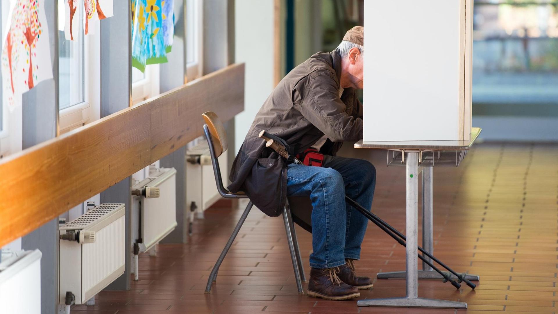 Ein älterer Mann sitzt in einer Wahl-Kabine Ein älterer Mann sitzt in einer Wahl-Kabine