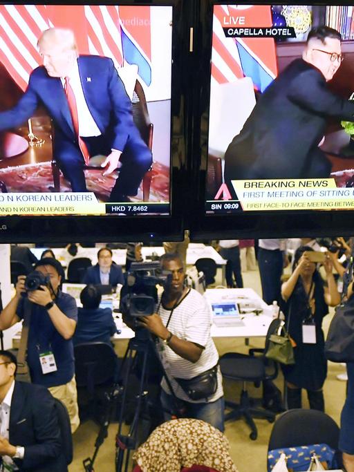 Journalisten im Pressezentrum in Singapur - vor Bildschirmen mit Nordkoreas Machthaber Kim Jong Un und US-Präsident Donald Trump