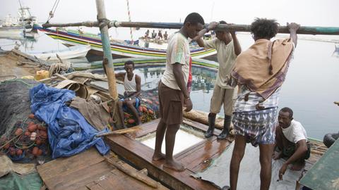 Arbeiter stehen an Deck eines Botes im Fischereihafen von Massawa, Eritrea