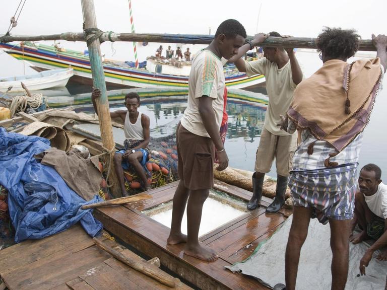 Arbeiter stehen an Deck eines Botes im Fischereihafen von Massawa, Eritrea
