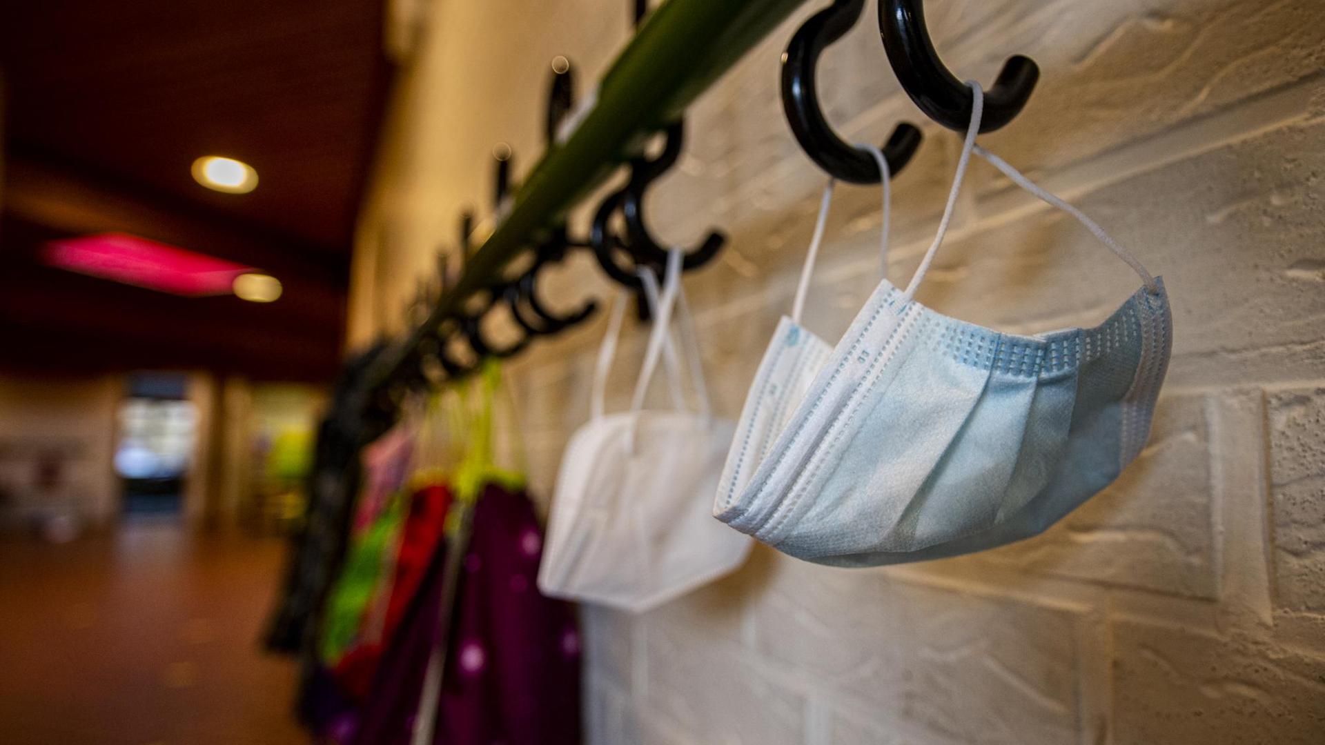 Mundmasken und Jacken hängen im Flur der Schule an einem Kleiderhaken. Die Schulen bleiben während des Corona-Lockdowns geschlossen. Mundmasken und Jacken hängen im Flur der Schule an einem Kleiderhaken. Die Schulen bleiben während des Corona-Lockdowns geschlossen.