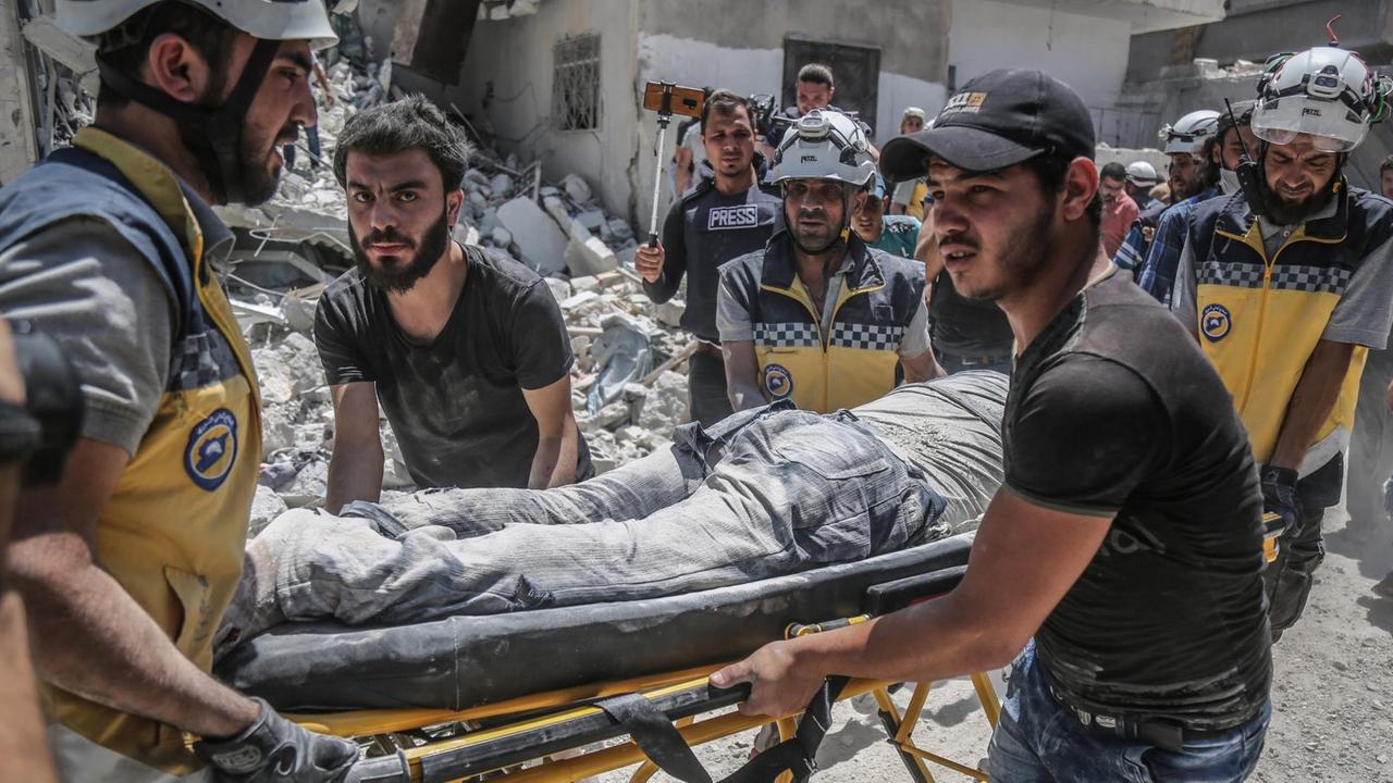 Mitglieder der "Weißhelme" bringen ein Opfer nach einem Luftangriff aus einem getroffenen Gebäude.