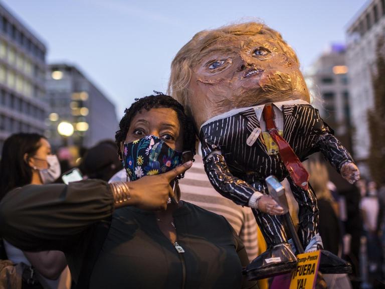 Eine schwarze Wählerin in Washington freut sich über das Ende der Präsidentschaft von Donald Trump und trägt eine Puppe des Noch-Präsidenten auf der Schulter.