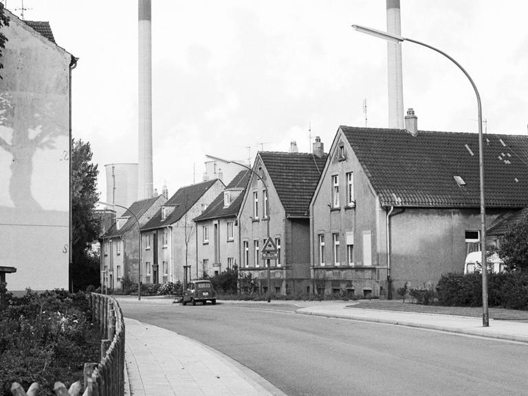 Häuser einer Arbeitersiedlung in Gelsenkirchen in Nordrhein-Westfalen, im Hintergrund Schornsteine einer Fabrik