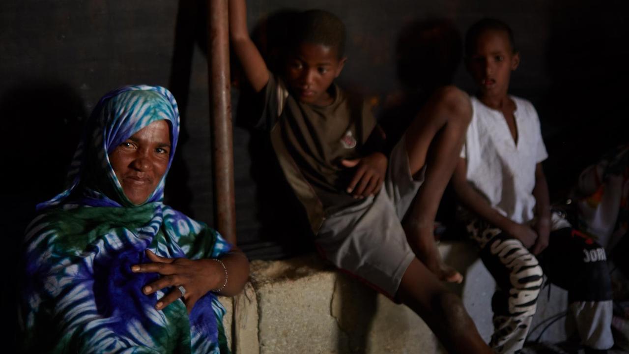 Die ehemalige Sklavin Haby Rabah und ihre beiden Söhne sitzen in ihrem dunklen Haus
