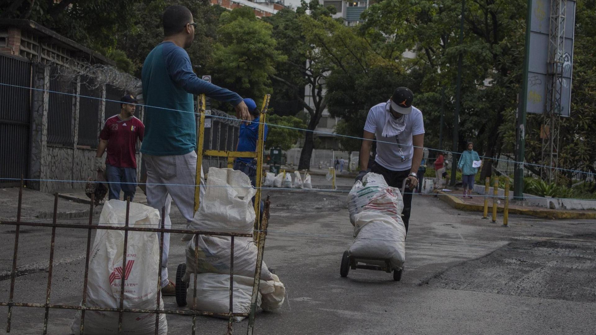 In Caracas sammeln mehrere Menschen in Säcken Bauschutt, um damit Barrikaden zu errichten. In Caracas sammeln mehrere Menschen in Säcken Bauschutt, um damit Barrikaden zu errichten.