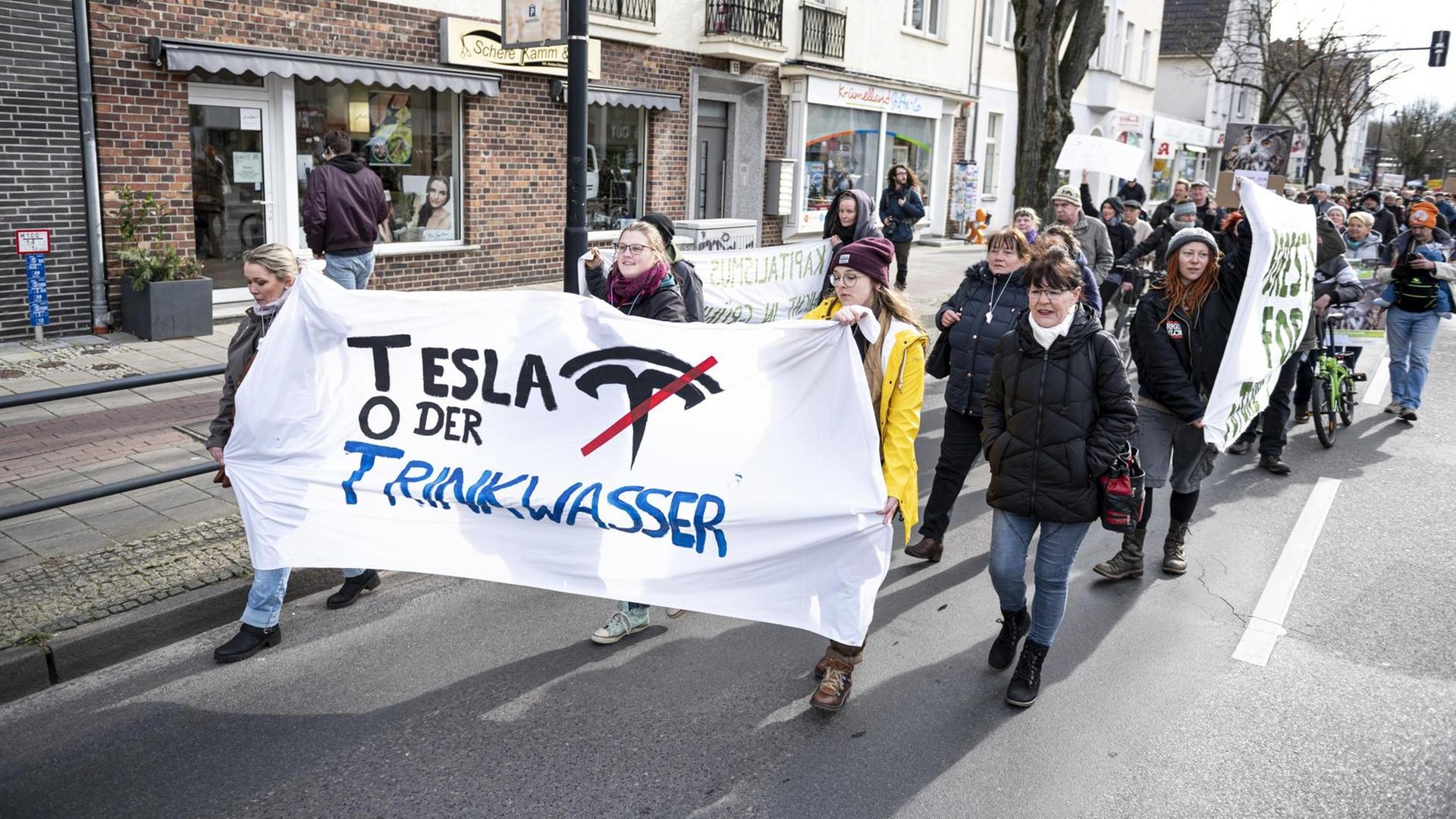 Demonstranten halten auf einer Demo gegen die geplante Tesla-Fabrik in Grünheide ein Banner mit der Aufschrift "Tesla oder Trinkwasser".