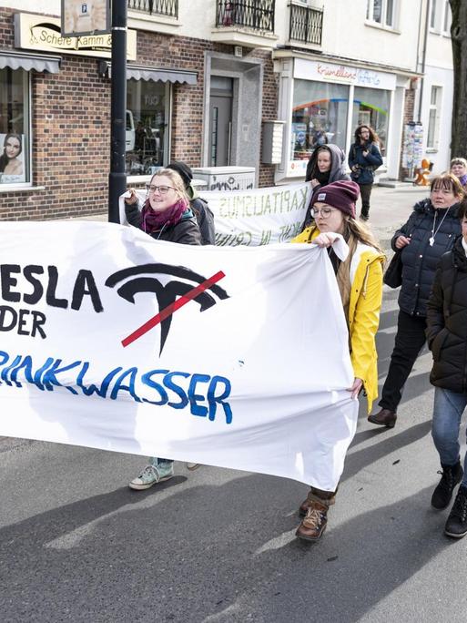 Demonstranten halten auf einer Demo gegen die geplante Tesla-Fabrik in Grünheide ein Banner mit der Aufschrift "Tesla oder Trinkwasser".
