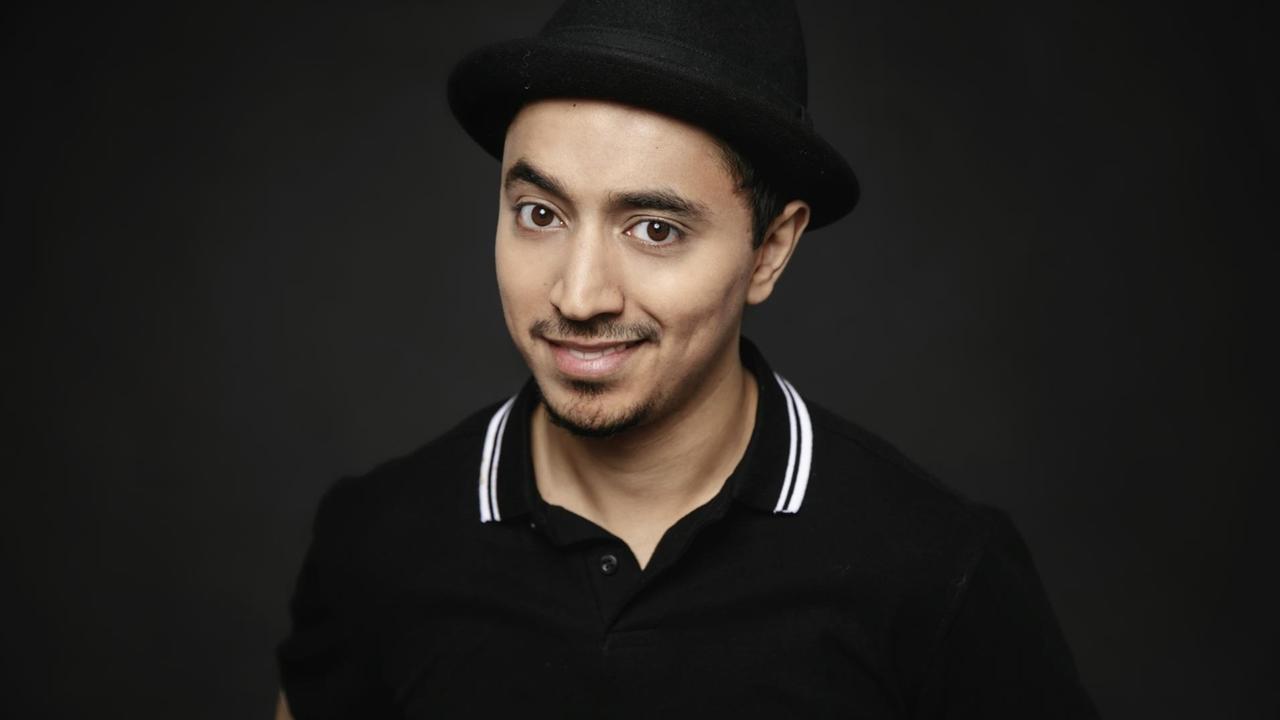 Porträt des Comedians Salim Samatou, er trägt einen schwarzen Hut