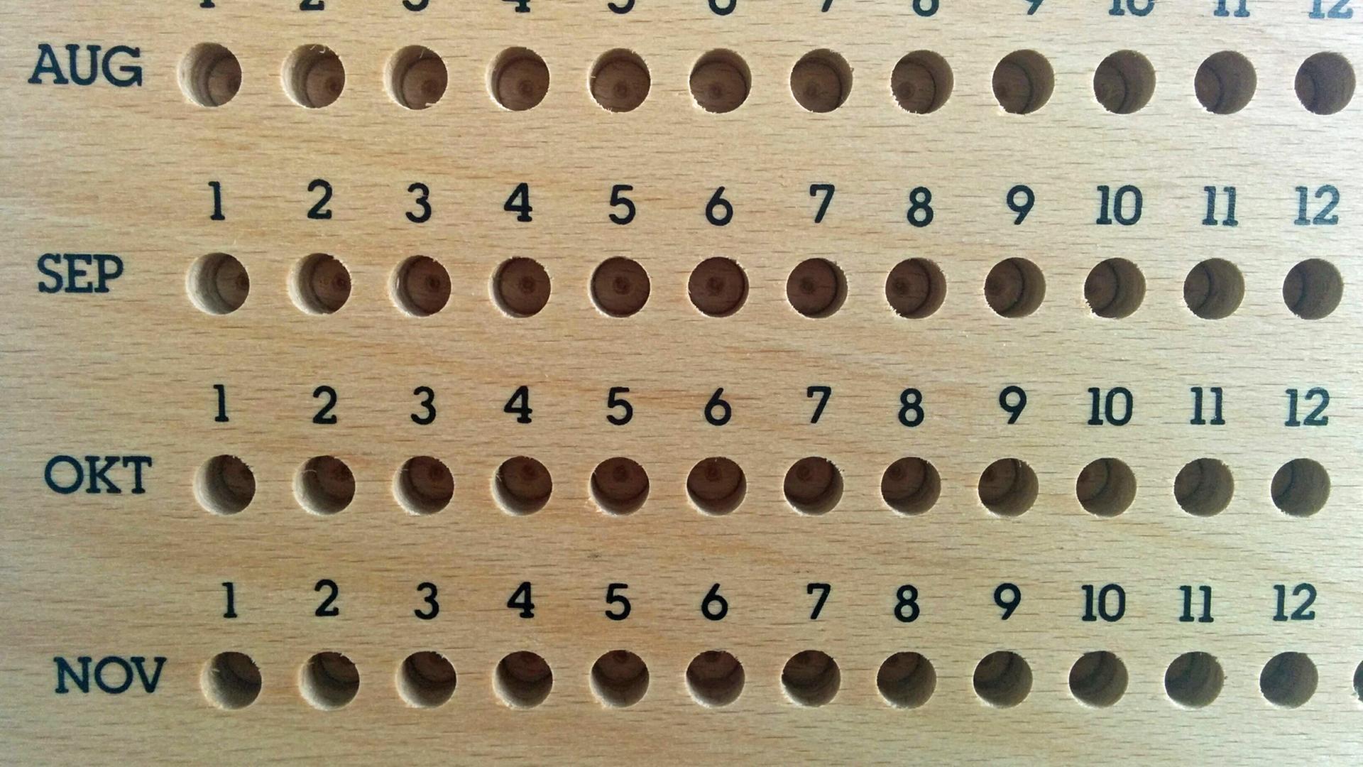 Ein ewiger Kalender aus Holz, zu sehen sind die Monate August, September, Oktober und November