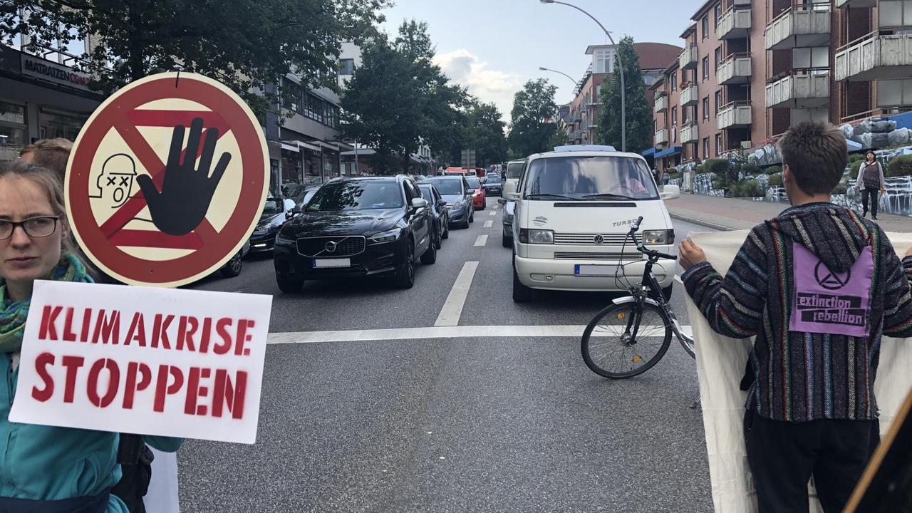 Straßenblockade der Klimabewegung Extinction Rebellion im Sommer 2019 in Hamburg. Menschen blockieren mit Plakaten in der Hand eine Straße. 