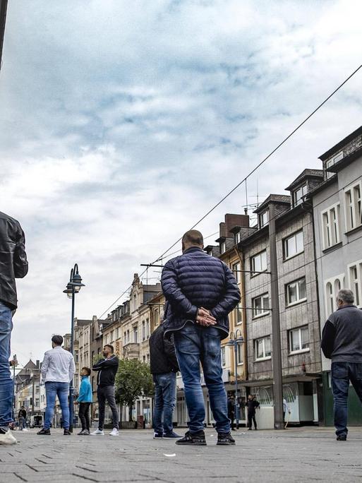 Auf einer gepflasterten Straße in Duisburg-Marxloh stehen einige Männer mit dem Rücken zur Kamera.
