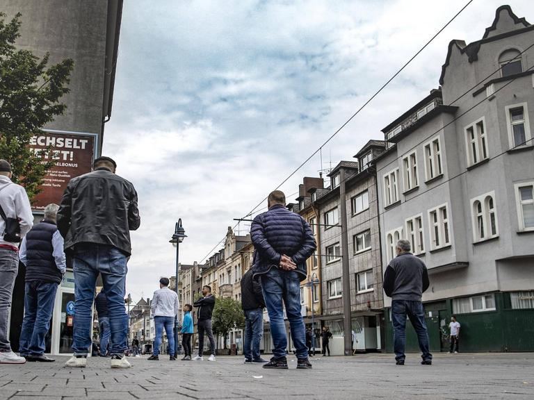 Auf einer gepflasterten Straße in Duisburg-Marxloh stehen einige Männer mit dem Rücken zur Kamera.