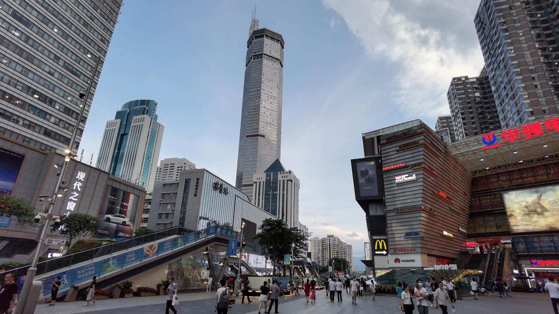 Das 300 Meter hohe SEG Plaza-Gebäude in Shenzhen (China). Auf dem Vorplatz sind Menschen unterwegs.