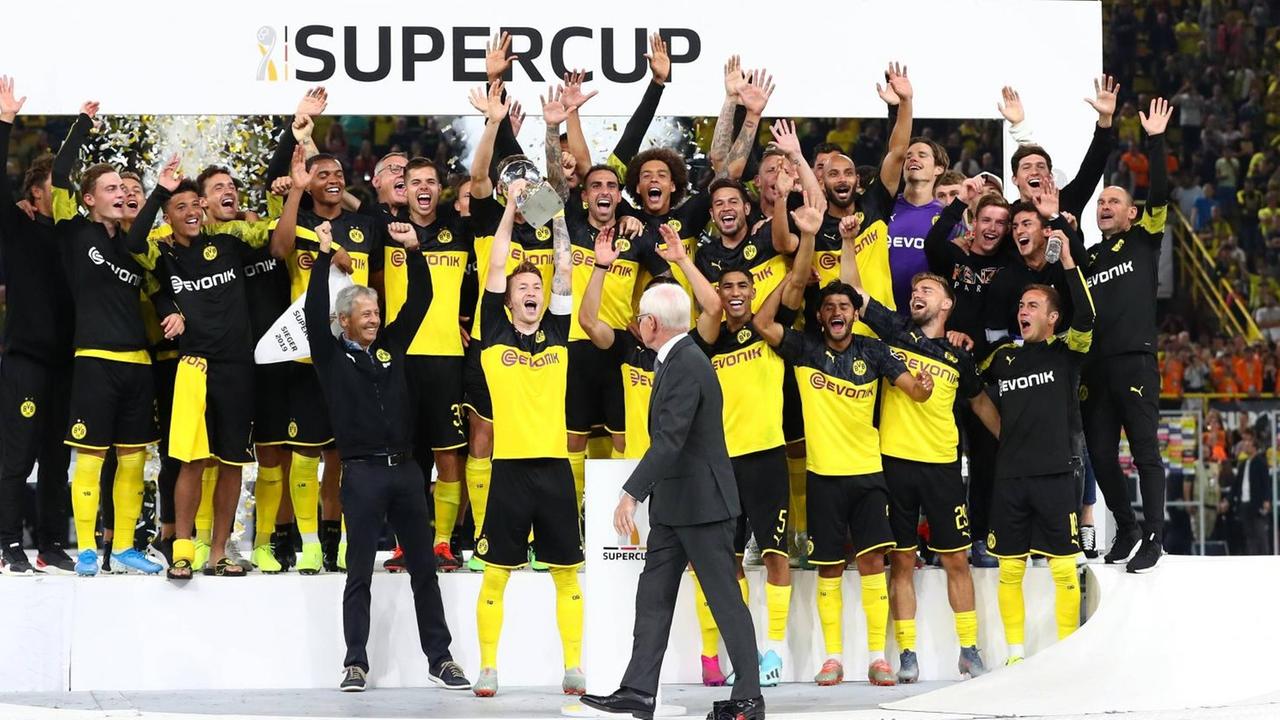 Das Foto zeigt den Jubel der Dortmunder Spieler nach Abpfiff des Supercups und die Präsentation des Pokals am 3. August 2019. Lucien Favre (BVB, Trainer) und der Kapitän Marco Reus (BVB) recken den Pokal in die Höhe.
