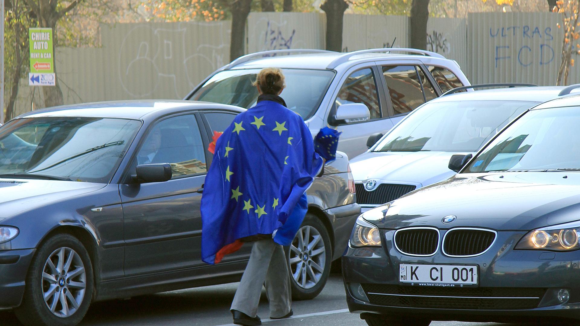 Richtungswahl: Eine junge Frau verteilt Moldau- und EU-Wimpel an Autofahrer im Stadtzentrum von Chisinau.