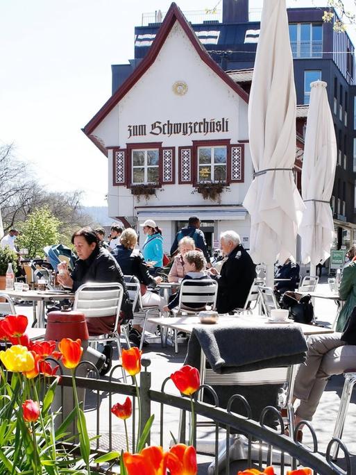 Bei frühlingshaftem Wetter sitzen Gäste in der idylischen schweizer Kleinstadt Baden draußen an Tischen vor einem Restaurant namens "Zum Schwyzerhüsli".