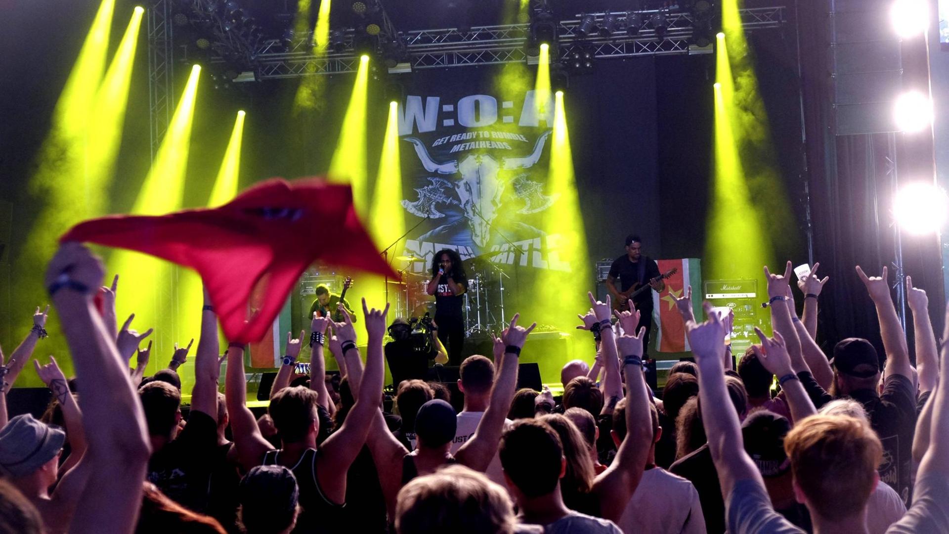 Asylum live auf dem 29. Wacken Open Air Festival - man kann einen Teil der Bühne sehen sowie die ersten Reihen des Publikums. Die Besucher halten die Hände in die Luft. Asylum live auf dem 29. Wacken Open Air Festival - man kann einen Teil der Bühne sehen sowie die ersten Reihen des Publikums. Die Besucher halten die Hände in die Luft.