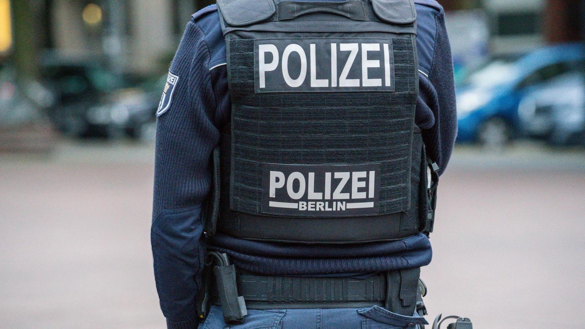 Ein Polizist der Berliner Polizei mit Schutzweste von hinten (Symbolbild)