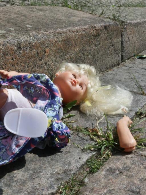 Eine kaputte Puppe liegt im Rinnstein - Symbolbild für den sexuellen Missbrauch von Kindern.
