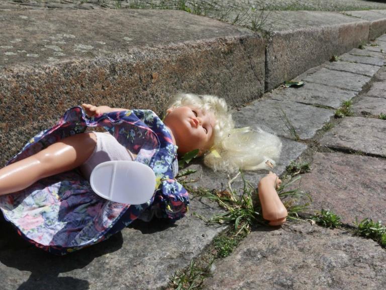 Eine kaputte Puppe liegt im Rinnstein - Symbolbild für den sexuellen Missbrauch von Kindern.