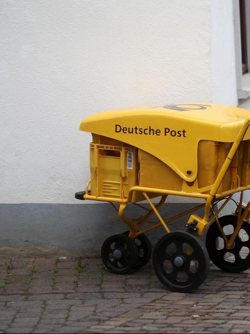 An einer Straßenecke in Idstein (Hessen) steht ein Briefzustellerwagen der Deutschen Post.