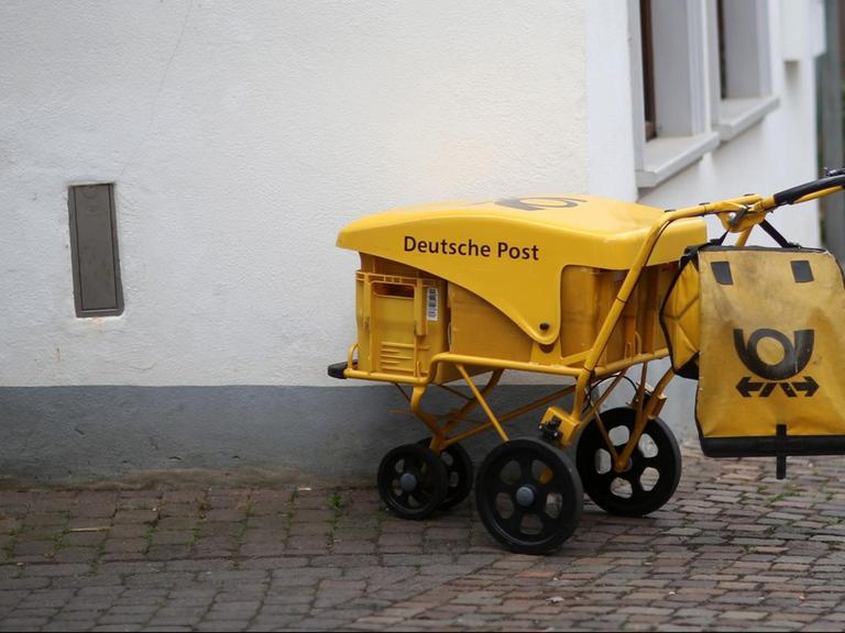 An einer Straßenecke in Idstein (Hessen) steht ein Briefzustellerwagen der Deutschen Post.