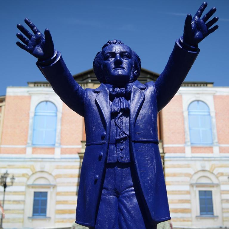 Ein Plastik-Wagner des Künstlers Ottmar Hörl "dirigiert" vor dem Königsportal des Festspielhauses auf dem Grünen Hügel in Bayreuth (Bayern).