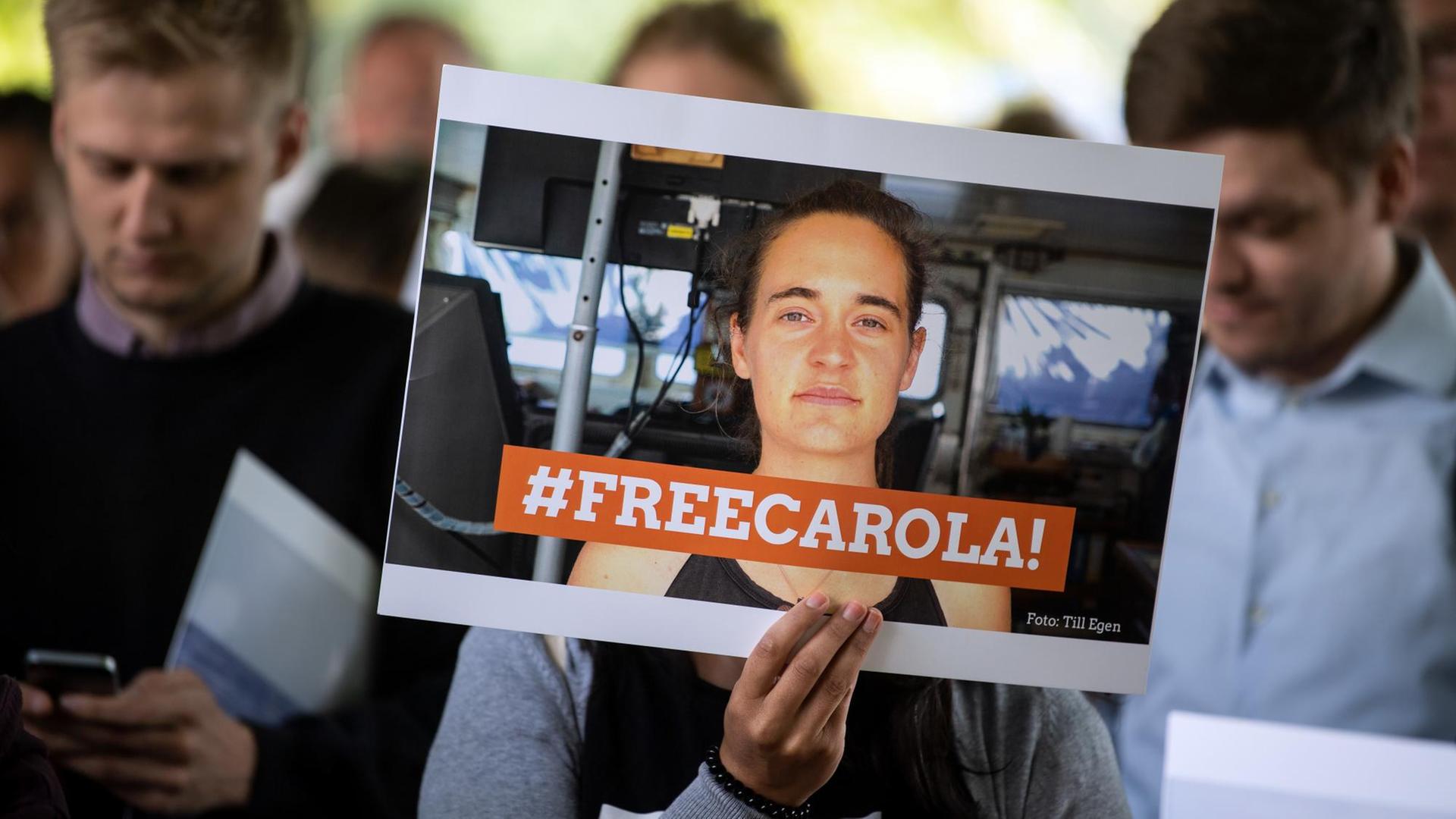 Eine Demonstrantin hält ein Bild von der Sea-Watch-Kapitänin Carola Rackete mit der Aufschrift "#FREECAROLA!" in der Hand.