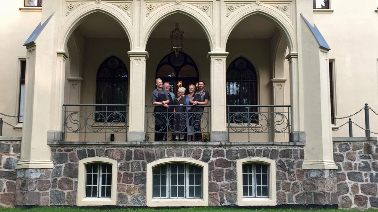 Jan Henrik Eilers und dessen Eltern stehen mit dem restlichen Team vom Schlosshotel Reichenow auf einem Balkon.