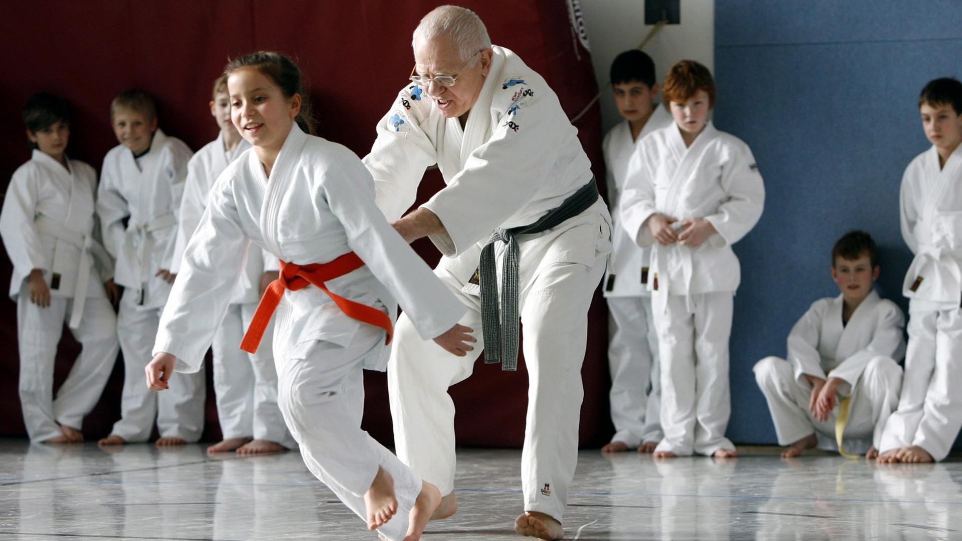 Eine Schülerin zieht während des Judo Unterrichts ihren Lehrer über die Judomatte
