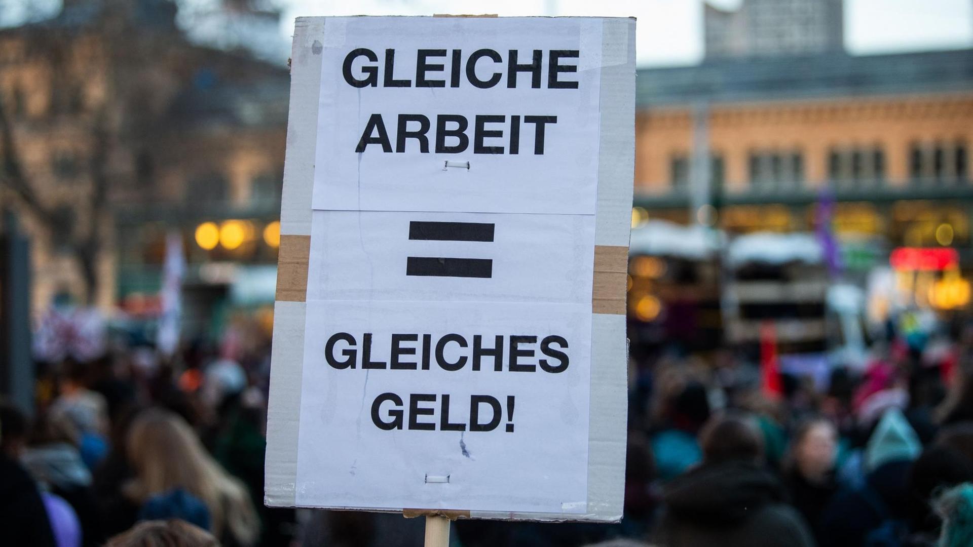 Eine Frau hält bei einer Demonstration am Weltfrauentag ein Plakat mit der Aufschrift "Gleiche Arbeit - gleiches Geld". Eine Frau hält bei einer Demonstration am Weltfrauentag ein Plakat mit der Aufschrift "Gleiche Arbeit - gleiches Geld".