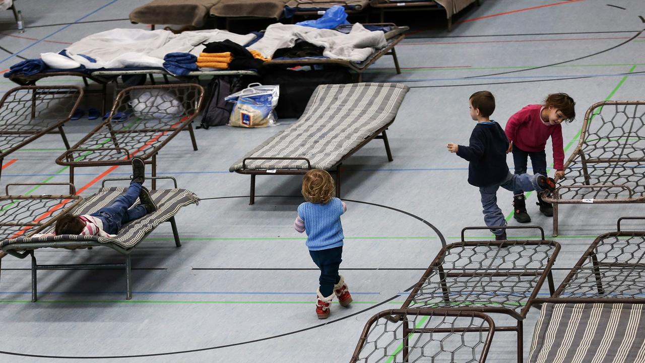 Flüchtlingskinder spielen am 19.02.2015 in der zur Notunterkunft für Asylbewerber umfunktionierten Frankenhalle in Neustadt bei Coburg (Bayern) zwischen den Feldbetten.